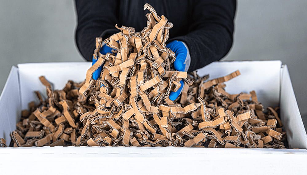 Opérateur utilisant un matelasseur de cartons pour transformer des emballages usagés en matériau de calage recyclé
