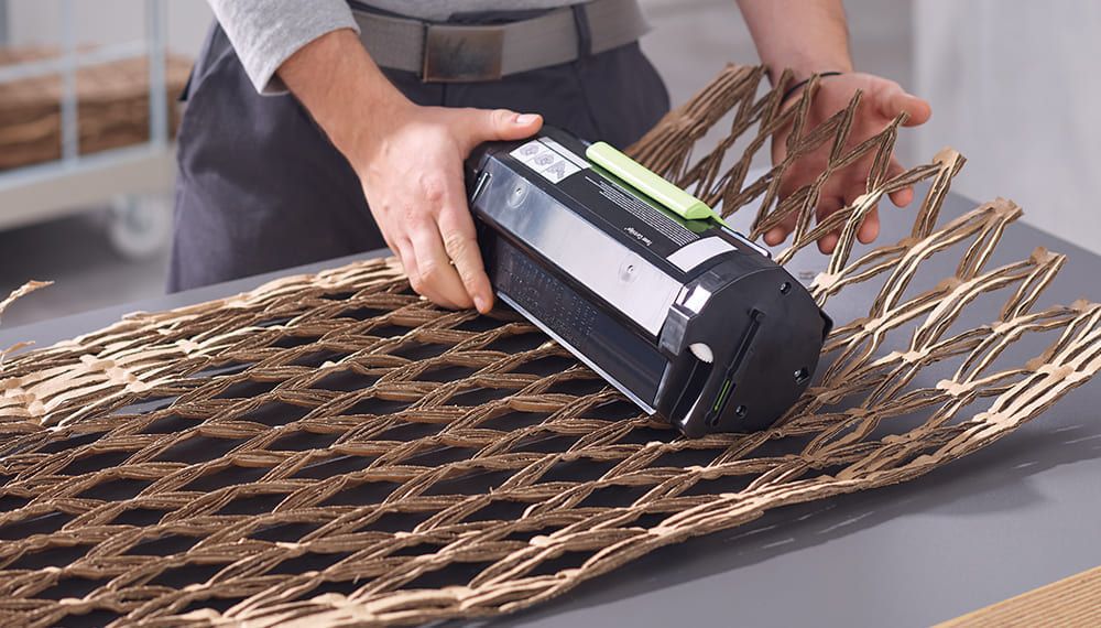 Opérateur utilisant un matelasseur de cartons pour transformer des emballages usagés en matériau de calage recyclé